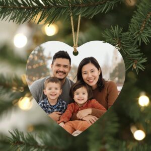 Smiling family portrait inside a heart-shaped Christmas ornament on a decorated tree.